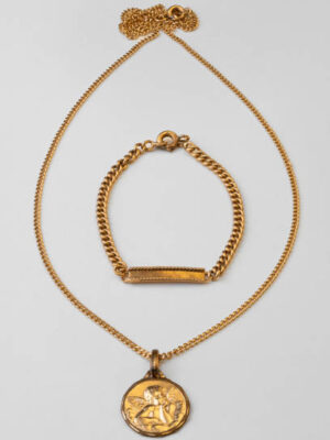 Still life. studio shot of a child golden gourmette, chain and medal